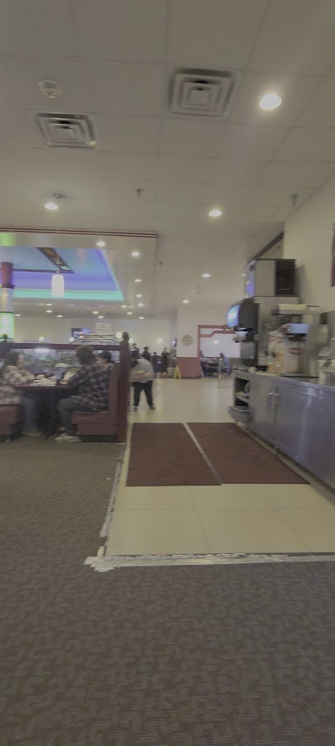 Sushi bar beside trays of hot buffet food.